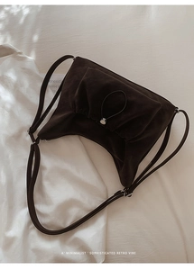 Detail of matte suede shoulder bag with vintage pleats and silver metal hardware