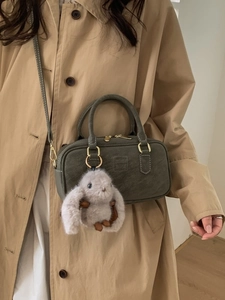 Chic dark green Boston pillow bag with cute plush bunny charm and crossbody strap