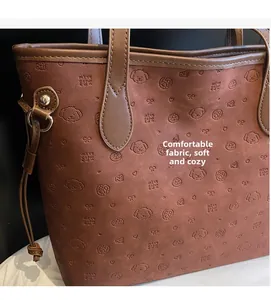 Close-up of rust red tote bag featuring embossed cartoon patterns and soft matte texture