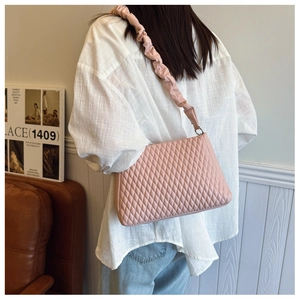 Detail of light pink quilted shoulder bag with unique ruched strap on model