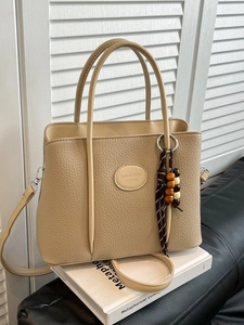 Elegant beige lychee grain bucket bag with wooden bead charm and adjustable strap