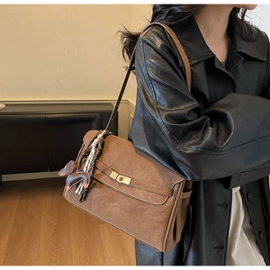 Detail of vintage brown tote bag featuring gold buckle and cute puppy charm on shoulder strap