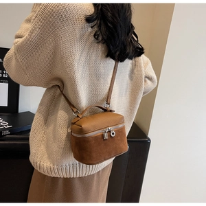 Detailed back view of a brown leather vanity crossbody bag on a model's shoulder