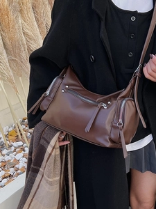 Vintage brown shoulder bag with silver studs and zipper detail shown in a rustic outdoor setting