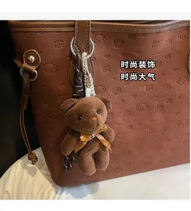 Brown plush bear keychain accessory with printed bow on large tote bag detail