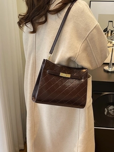 Deep brown quilted faux leather shoulder bag with gold clasp shown on model