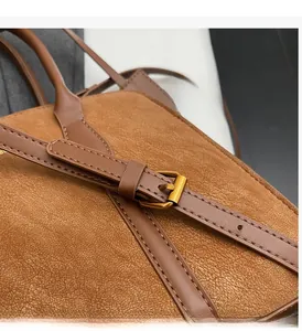 Detail der braunen Leder-Tragetasche mit goldener Schnalle und feinen Nähten