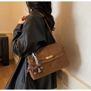 Dark brown tote bag detail with golden metal clasp and woven rope accent