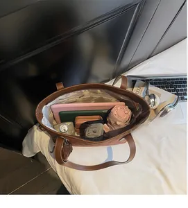 Detailed interior of a large brown leather tote showing storage for tablets and essentials