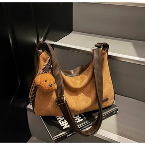 Dettaglio della borsa tote in pelle e scamosciato con un simpatico ciondolo a orsetto