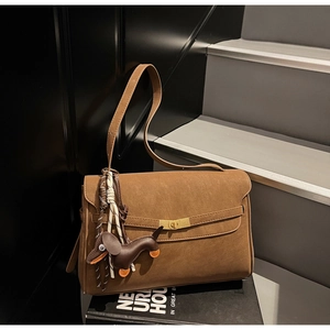 Detail of a brown suede tote bag with metal twist lock and cute dachshund leather charm