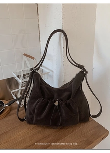 Detail shot of a dark brown suede retro shoulder bag featuring a drawstring and magnetic buckle