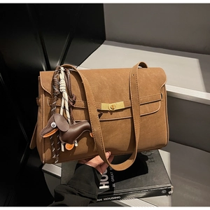 Brown tote bag with a golden clasp and a cute dachshund charm on stone stairs