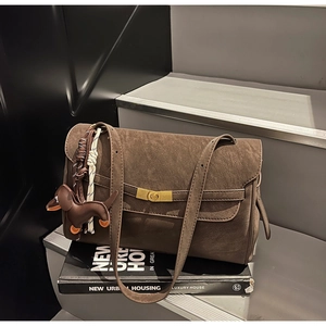 Detail of dark brown tote bag featuring golden twist lock and leather dog charm accessory