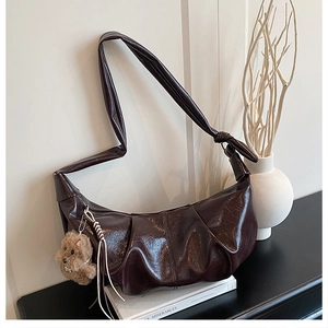 Detail of dark coffee pleated dumpling bag in glossy patent leather with bear charm