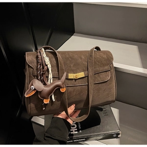 Detail of dark brown textured tote bag with golden twist lock and dachshund leather charm