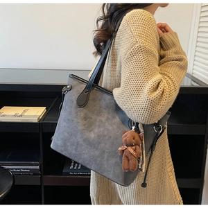Detail of grey tote bag with embossed puppy texture and plush bear charm pendant
