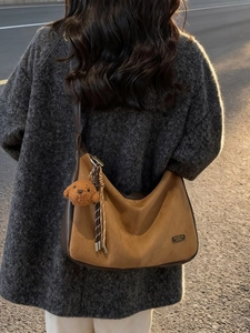 Borsa tote in camoscio marrone con ciondolo a cane e nappa su cappotto grigio
