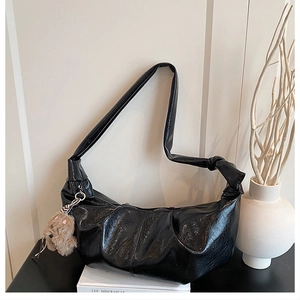 Detail of black pleated faux leather hobo bag featuring a knotted wide shoulder strap