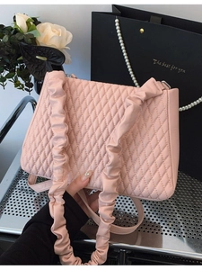 Pink quilted shoulder bag with pleated straps and rhombus pattern on a mesh surface