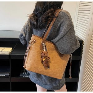 Detailed back view of a large brown tote bag with embossed dog patterns and bear charm