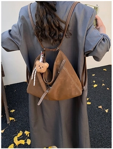 Detail of dark brown triangular folding backpack with contrast stitching and bear charm