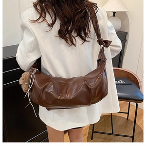 Brown oil wax leather pleated crossbody bag with plush charm and knot strap detail