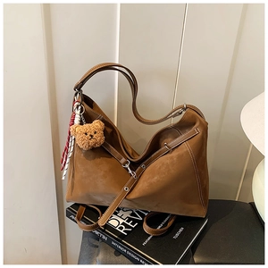 Detail of brown suede tote bag with white contrast stitching and cute bear charm