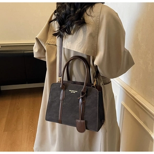 Detail der Vintage-Tragetasche mit strukturiertem Stoff, braunem Lederbesatz und Schultergurt
