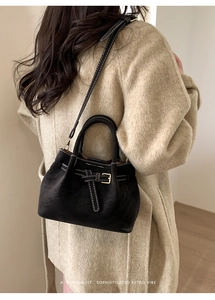 Detail of retro black suede tote bag with white contrast stitching and buckle accent