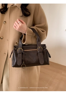 Détail d'un sac Boston en cuir marron foncé avec boucles en métal rétro