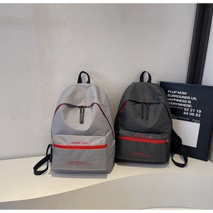 Detail of checkered plaid backpacks in grey and black with front red zipper pockets