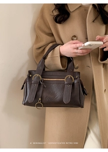Détail d'un sac porté épaule rétro marron foncé avec finitions dorées et cuir mat