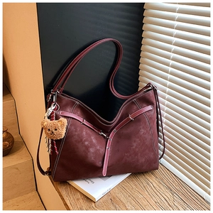 Detail of dark burgundy retro tote bag with suede texture and plush bear charm