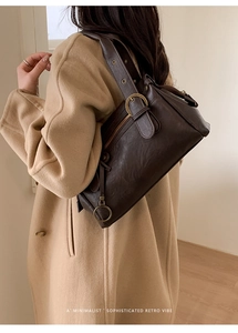 Détail d'un sac à bandoulière rétro marron foncé avec texture froissée et boucles dorées