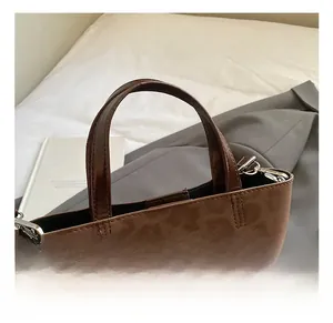 Detailed view of brown leopard print handbag with glossy strap and silver hardware