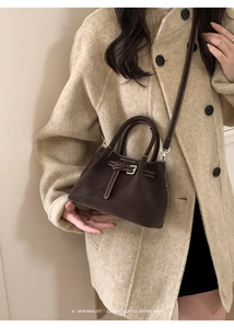 Close-up of retro bucket bag in dark brown suede with white contrast stitching detail