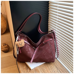 Close-up of burgundy suede tote bag with metal eyelets and cute brown teddy bear charm