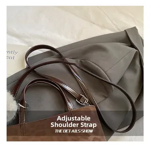 Detail of a brown animal textured bucket bag featuring an adjustable strap and plush charm