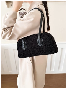 Détail du sac à épaule en peluche noire avec poignées en cuir et pieds de protection