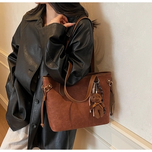 Detail of vintage brown tote bag with logo embossing and a cute teddy bear charm
