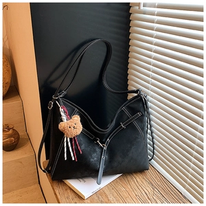 Detail of black suede tote bag featuring white contrast stitching and a cute bear charm