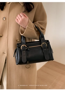 Détail du sac à bandoulière noir rétro avec boucles dorées porté par un mannequin