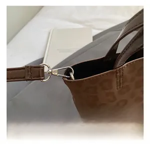 Detail of silver metal hook and detachable strap on leopard print bucket bag