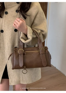 Détail d'un sac à main rétro en cuir marron avec boucles en métal et pendentif anneau