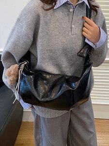 Large black pleated crossbody dumpling bag with ribbon and charm on model