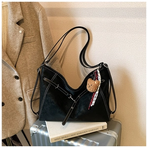 Detail of black tote bag with white contrast stitching and cute plush bear accessory
