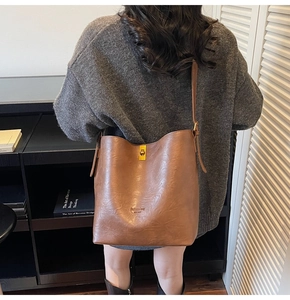 Close-up of vintage brown leather bucket bag featuring a metal clasp and fashion bag logo