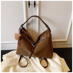 Detail of vintage brown tote bag with contrast stitching and plush bear charm