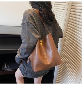 Detail of deep brown bucket bag with embossed New York text and metal buckle hardware